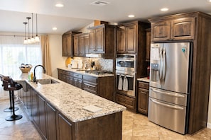 Una cocina moderna con armarios de madera oscura, electrodomésticos de acero inoxidable y encimera de granito.