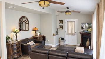 A living room with a sectional sofa, two ceiling fans, a television, and a fireplace.