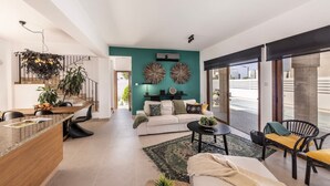 A modern living room with a teal accent wall, a white sofa, and a dining area with a wooden table and chairs. - SunnyVillas: 3BR New Modern Villa*Private Pool*HVN (Paralimni)