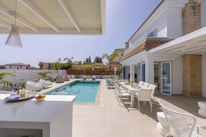 A poolside area with a dining table, lounge chairs, and a clear view of the pool.