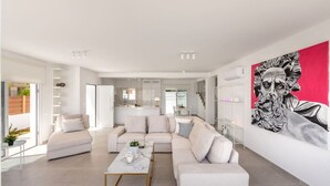 A modern living room with a beige sofa set, a coffee table, and a large abstract painting on the wall. - SunnyVillas: 3BR New Modern Villa*Private Pool*BLG (Paralimni)
