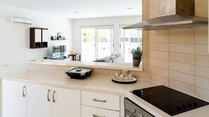 Une cuisine moderne dotée d’un îlot central, d’une cuisinière et d’un four à micro-ondes. Une fenêtre laisse entrer la lumière naturelle et offre une vue sur l’extérieur.