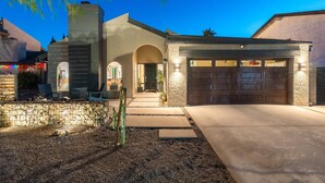 A modern house with a stone facade, a garage, and a pathway leading to the entrance. - Gorgeous Papago Retreat w/Pool (Phoenix)