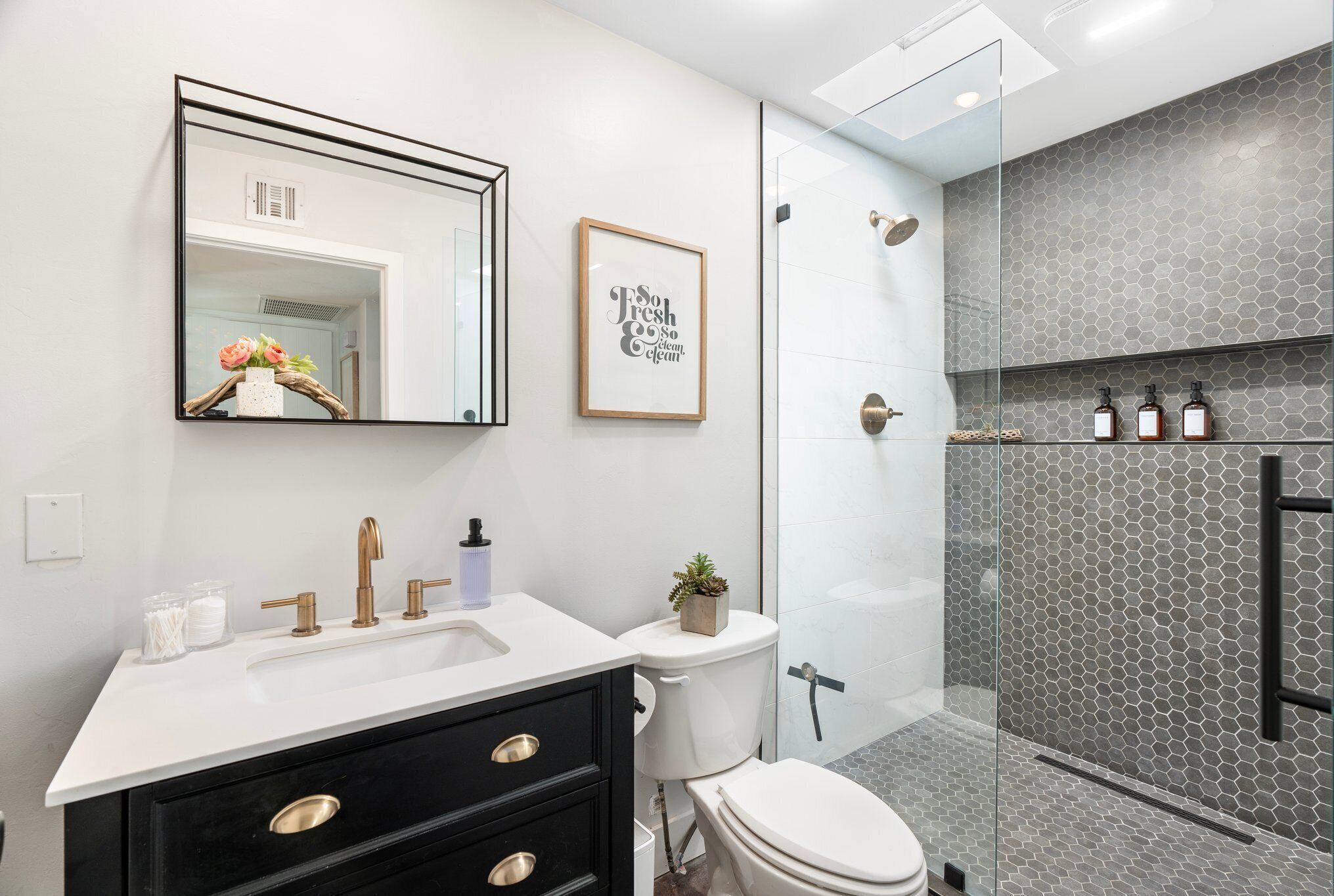 Une salle de bain moderne avec un lavabo blanc, un meuble-lavabo noir et une cabine de douche en verre.
