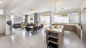 Une cuisine moderne avec un îlot central, un coin repas doté d’une table ronde et un salon avec un canapé et une table basse.