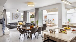 Un salon moderne comprenant un canapé, une table à manger et des chaises. Il y a également un coin cuisine avec un comptoir et un évier.