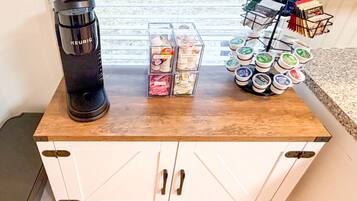 Un comptoir de cuisine avec une machine à café Keurig, un ensemble de boîtes de rangement transparentes et un présentoir à dosettes de café.
