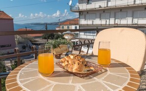 A table with a croissant and two glasses of orange juice, overlooking a coastal view with buildings and a clear sky. - Charming Apartment Domi (Okrug Gornji)