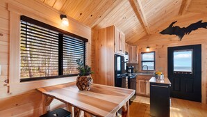 Ein Holzblockhaus-Innenraum mit Küche, Essbereich und Blick ins Freie.