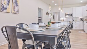 A modern kitchen with white cabinets, stainless steel appliances, and a dining area with a long table and chairs. - Perfect Spot to Relax 4br/3ba Near Dtown Hemisfair (San Antonio)