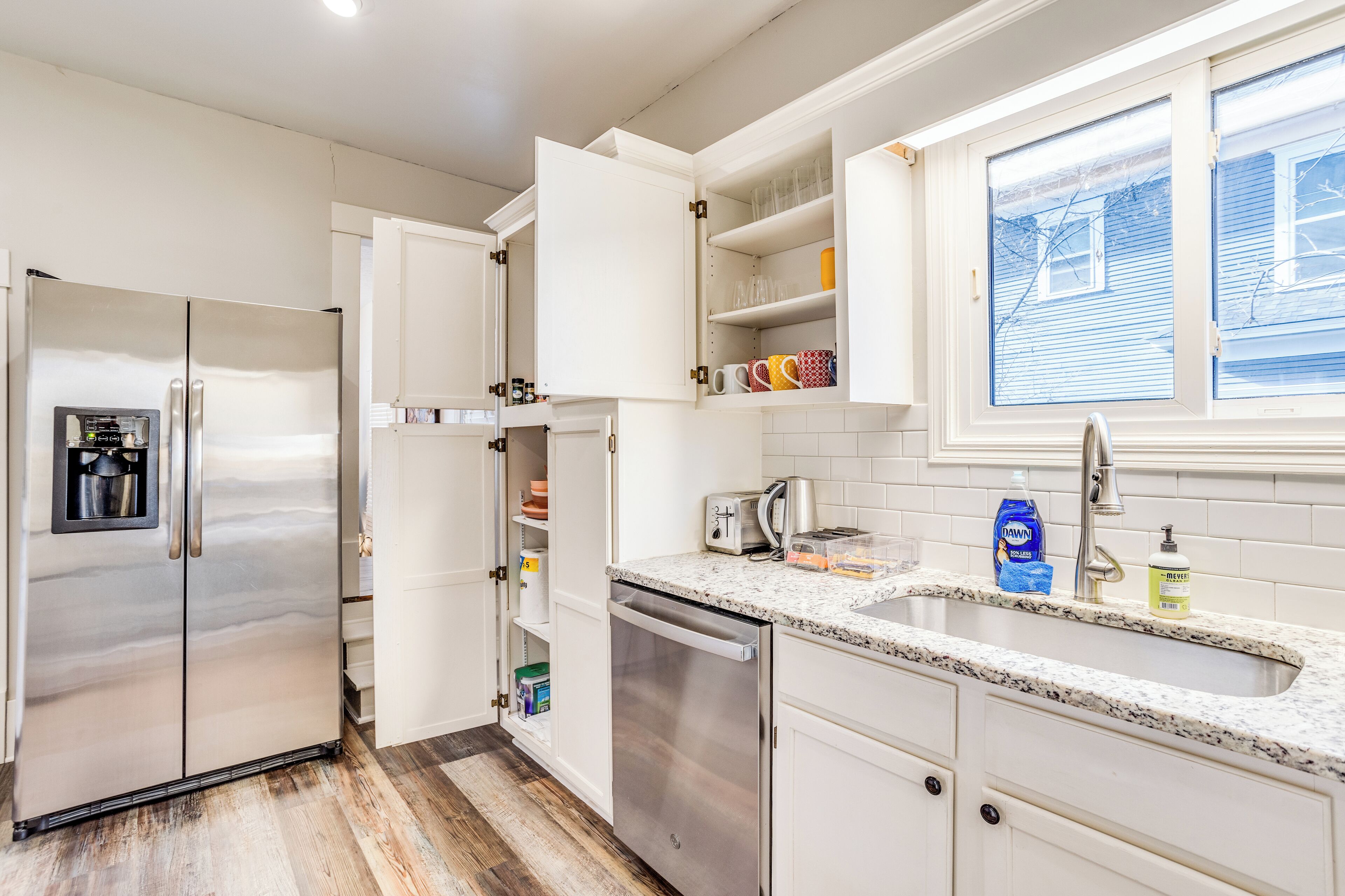A modern kitchen with stainless steel appliances, white cabinetry, and a granite countertop.