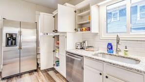 A modern kitchen with stainless steel appliances, white cabinetry, and a granite countertop. - Short Walk to Wesley Hospital | 3 Beds W/ W&D! (Wichita)