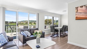 Un salon spacieux avec balcon, de grandes fenêtres et un coin repas.