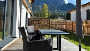 Eine Terrasse mit Korbmöbeln und einem Tisch, mit Blick auf ein Gebirge.