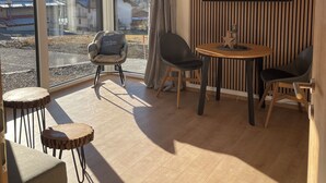 Ein modernes Zimmer mit großem Fenster, Flachbildfernseher und Holzboden.