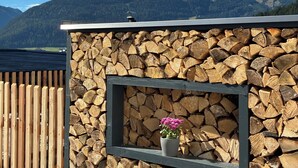 Eine Steinmauer mit einem Holzzaun, ein Fenster mit Blume und Blick auf die Berge.