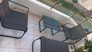 A balcony with four chairs and a table, overlooking a street with parked cars and greenery. - The house of happiness (Abidjan)