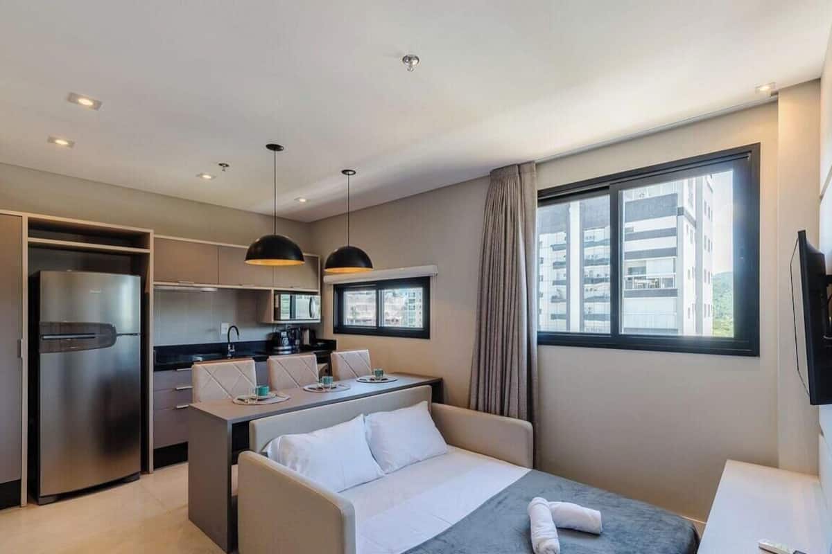 Une chambre d’hôtel équipée d’un lit, d’un bureau, d’une kitchenette et d’une grande fenêtre.
