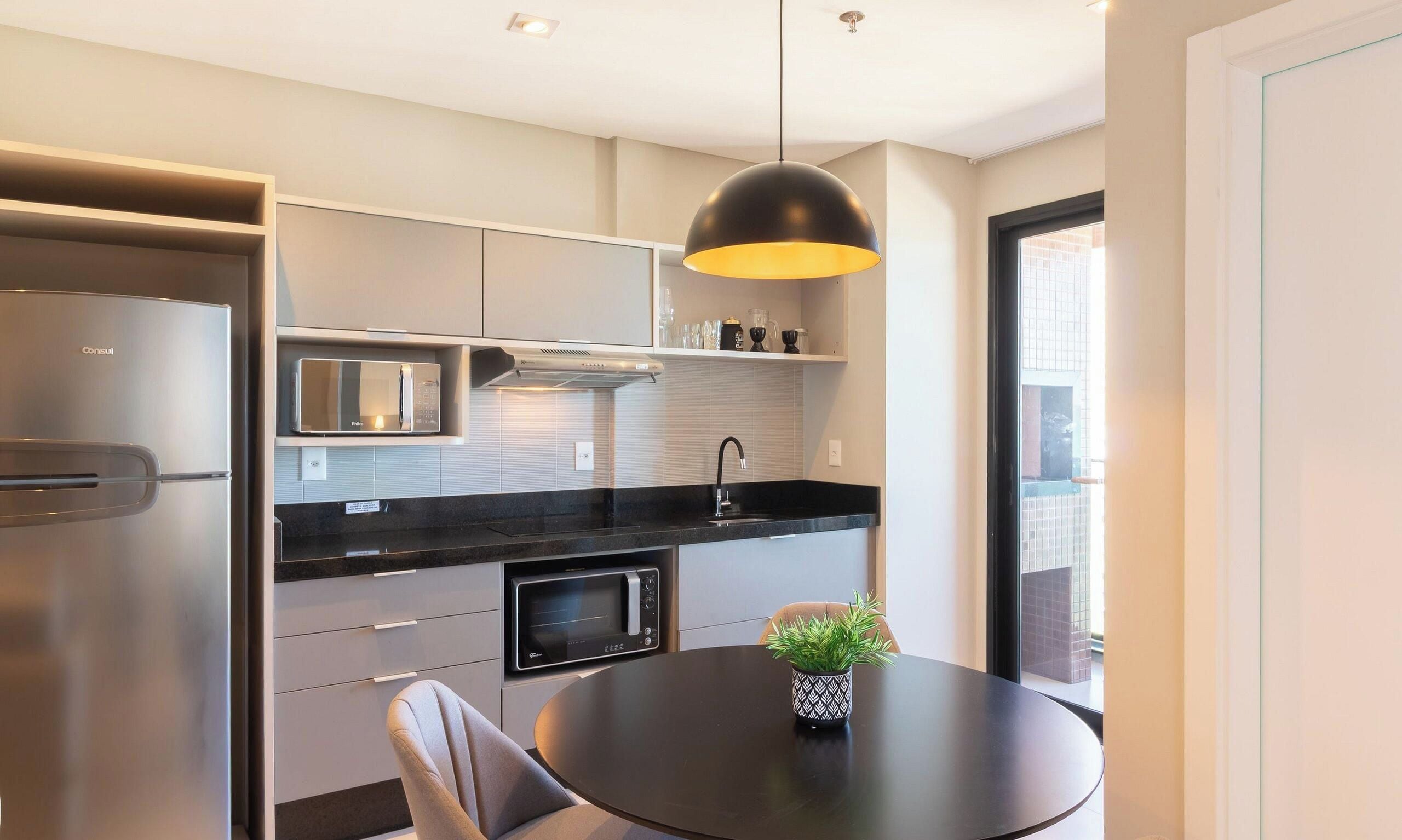 Una cocina moderna con microondas integrado, estufa y comedor con mesa y sillas.