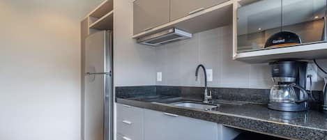 Una cocina moderna con refrigerador integrado, cafetera y tetera.