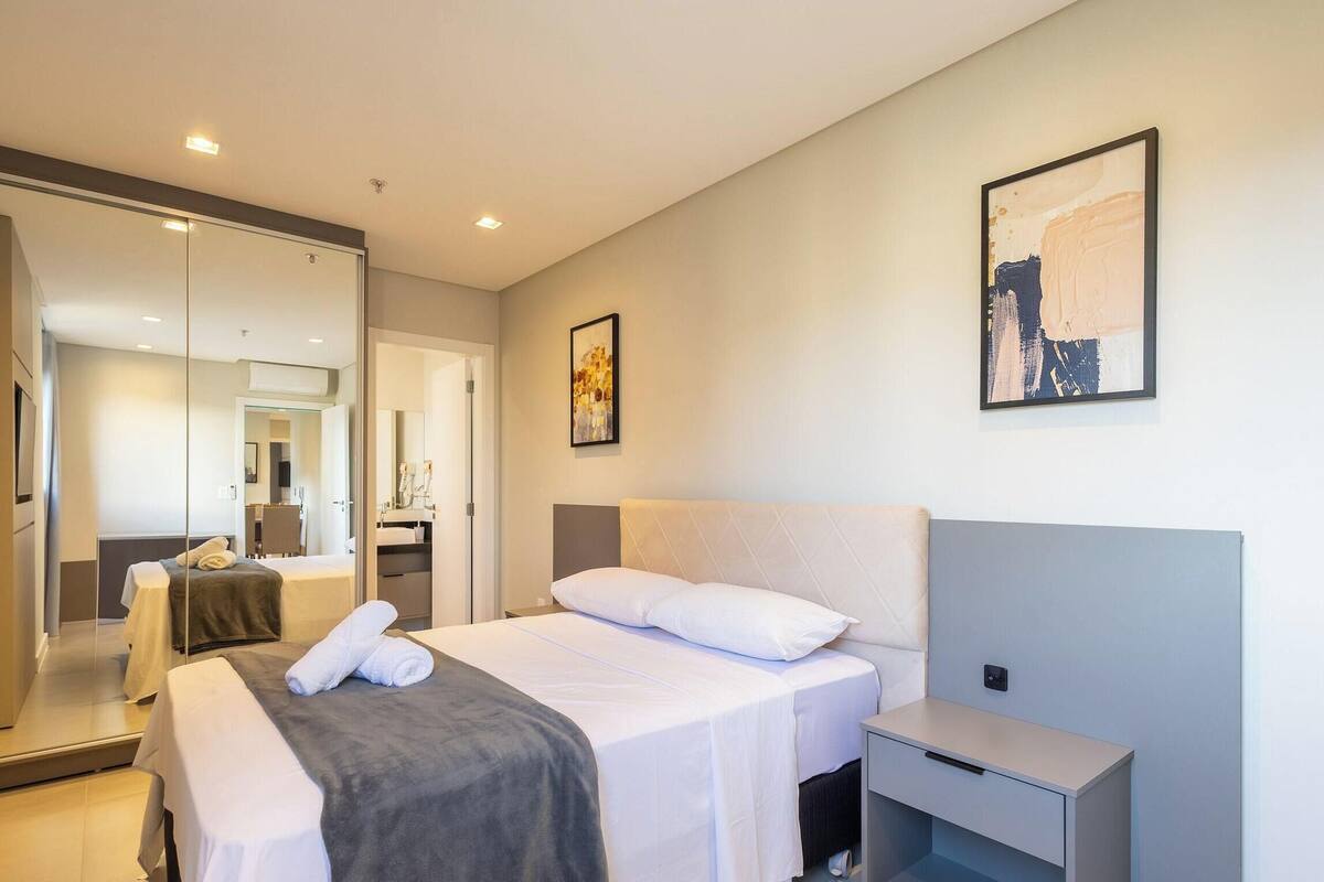 Une chambre d’hôtel avec un lit, une table de chevet et un miroir.