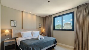 Une chambre d’hôtel comprenant un lit, des tables de chevet, une fenêtre avec des rideaux et des œuvres d’art accrochées au mur.