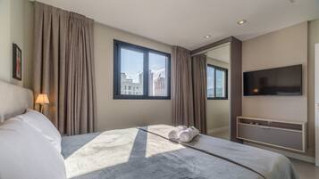 Een hotelkamer met een bed, een televisie, een bureau en een raam met gordijnen.