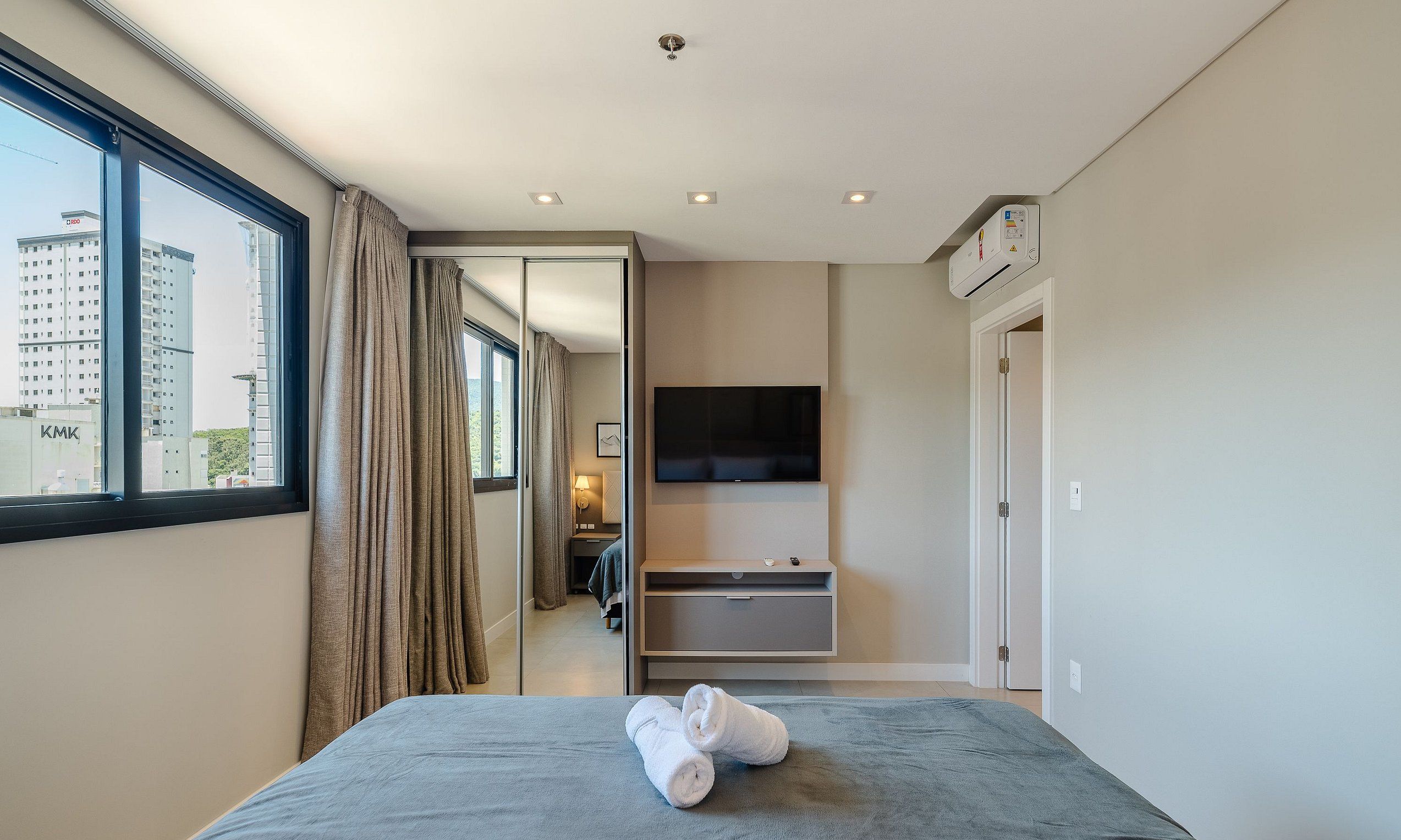 Habitación de hotel con cama, televisión, baño y vistas a un edificio.