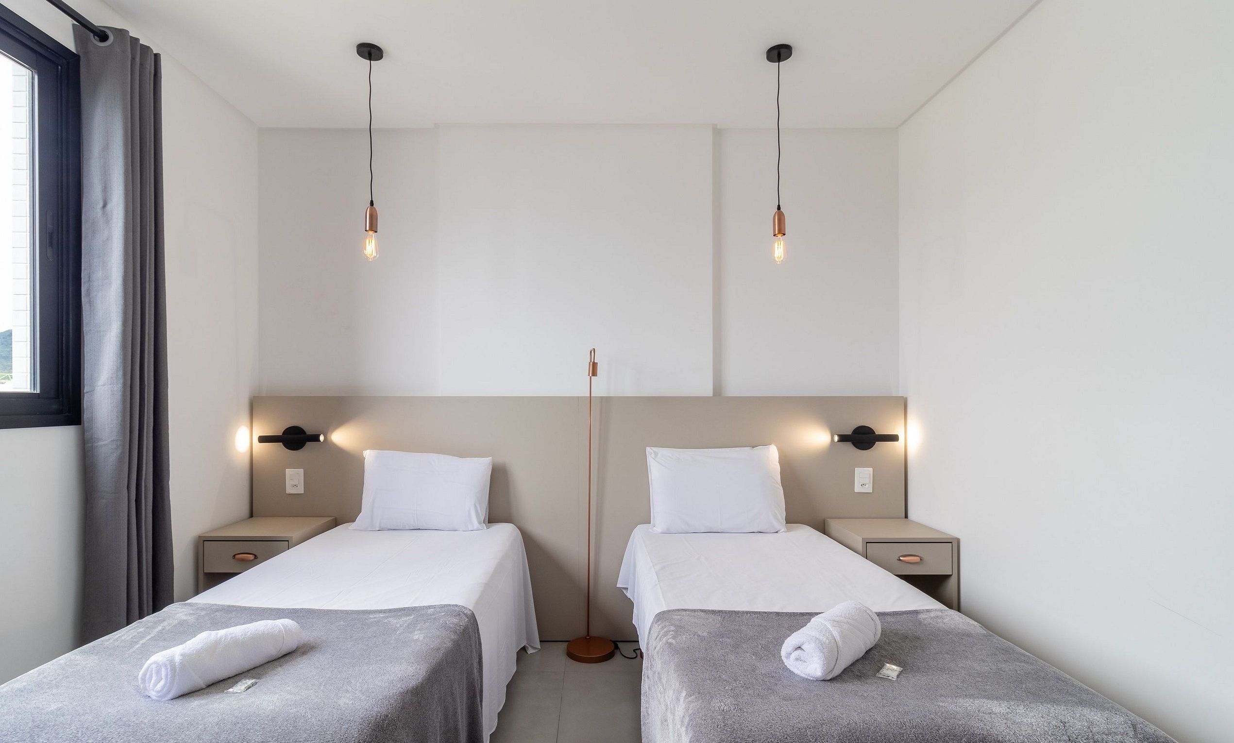 Ein Hotelzimmer mit zwei Einzelbetten, Nachttischen und einer Stehlampe.