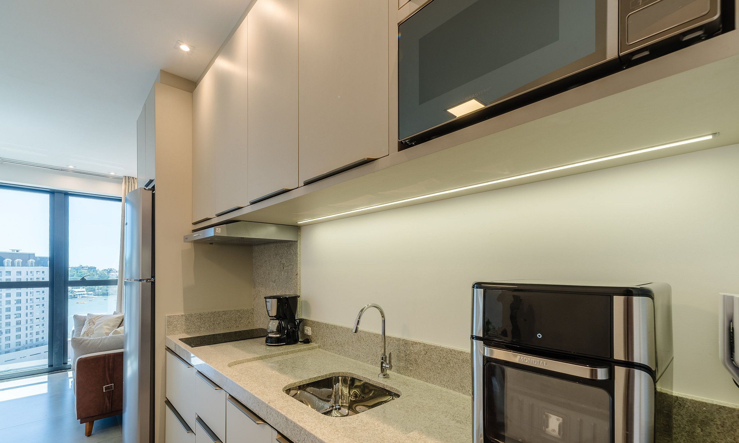 Una cocina moderna con estufa integrada, cafetera y refrigerador.
