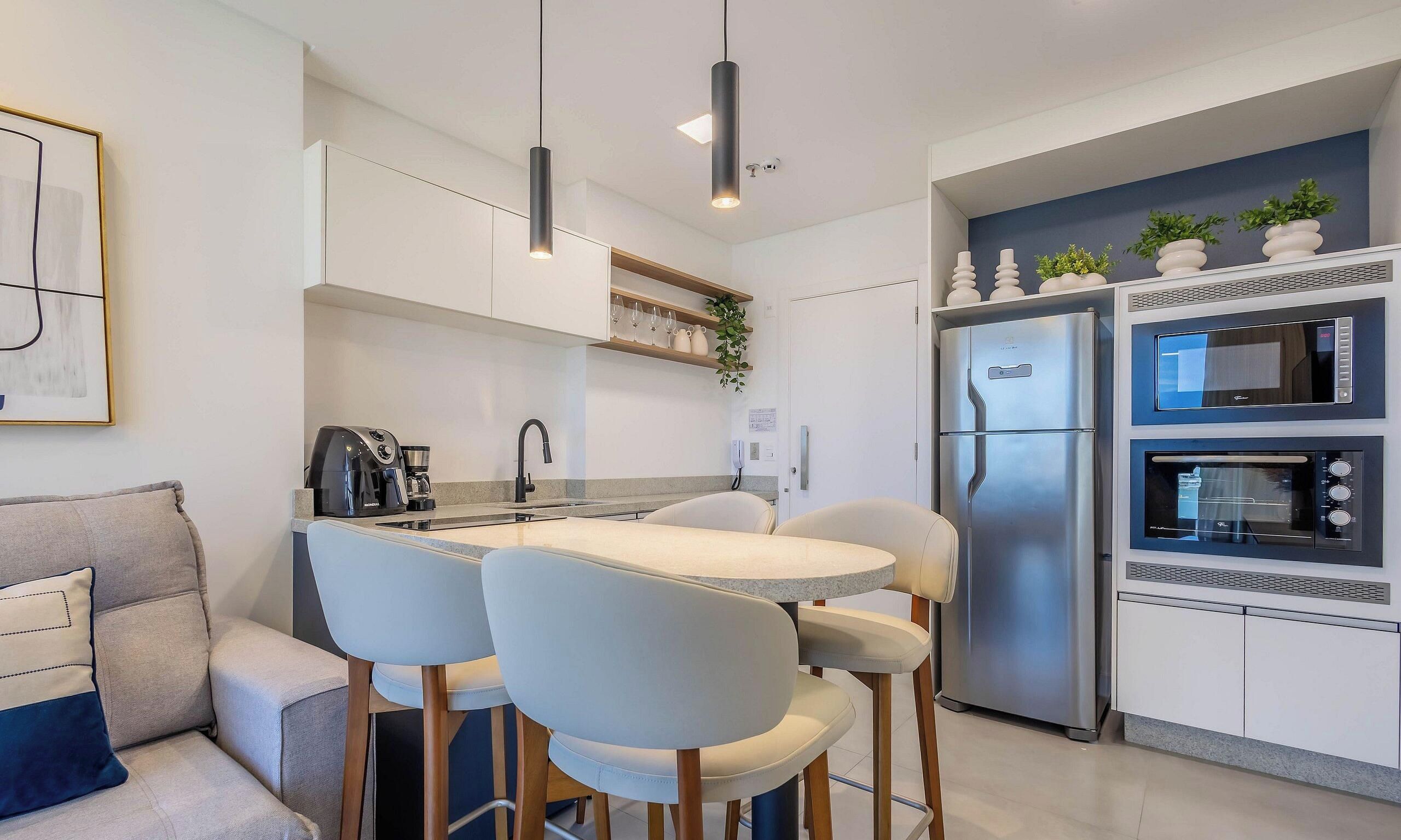 Een moderne keuken met een eettafel, stoelen, een koelkast en een magnetron.
