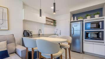 Een moderne keuken met een eettafel, stoelen, een koelkast en een magnetron.