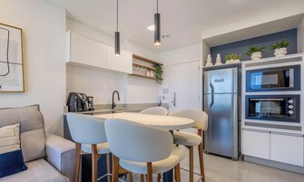 Una cocina moderna con una mesa de comedor, sillas, un refrigerador y un microondas.