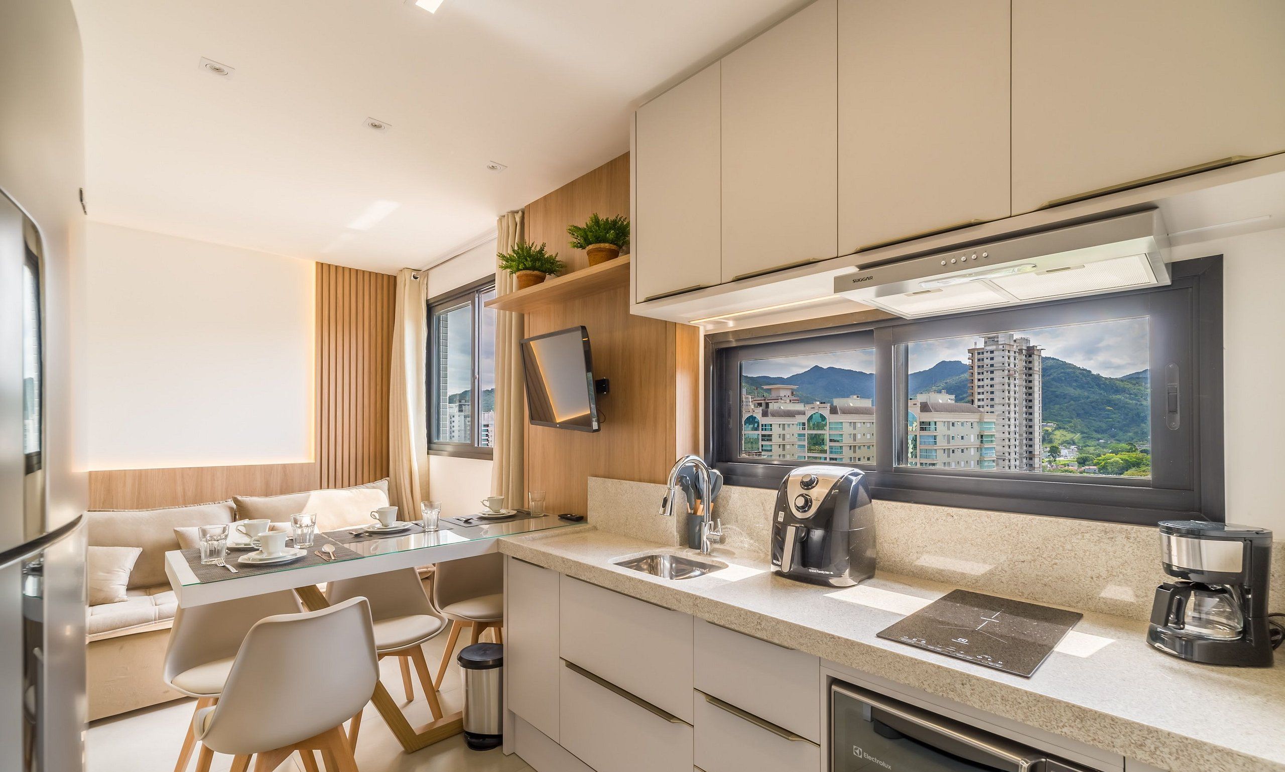 A modern kitchen with a view of a cityscape, equipped with a coffee maker, a toaster, and a sink.