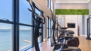 A gym with exercise equipment, large windows, and a view of the sea. - MHF III Apts Variados a 280m da Praia em Itapema (Itapema)