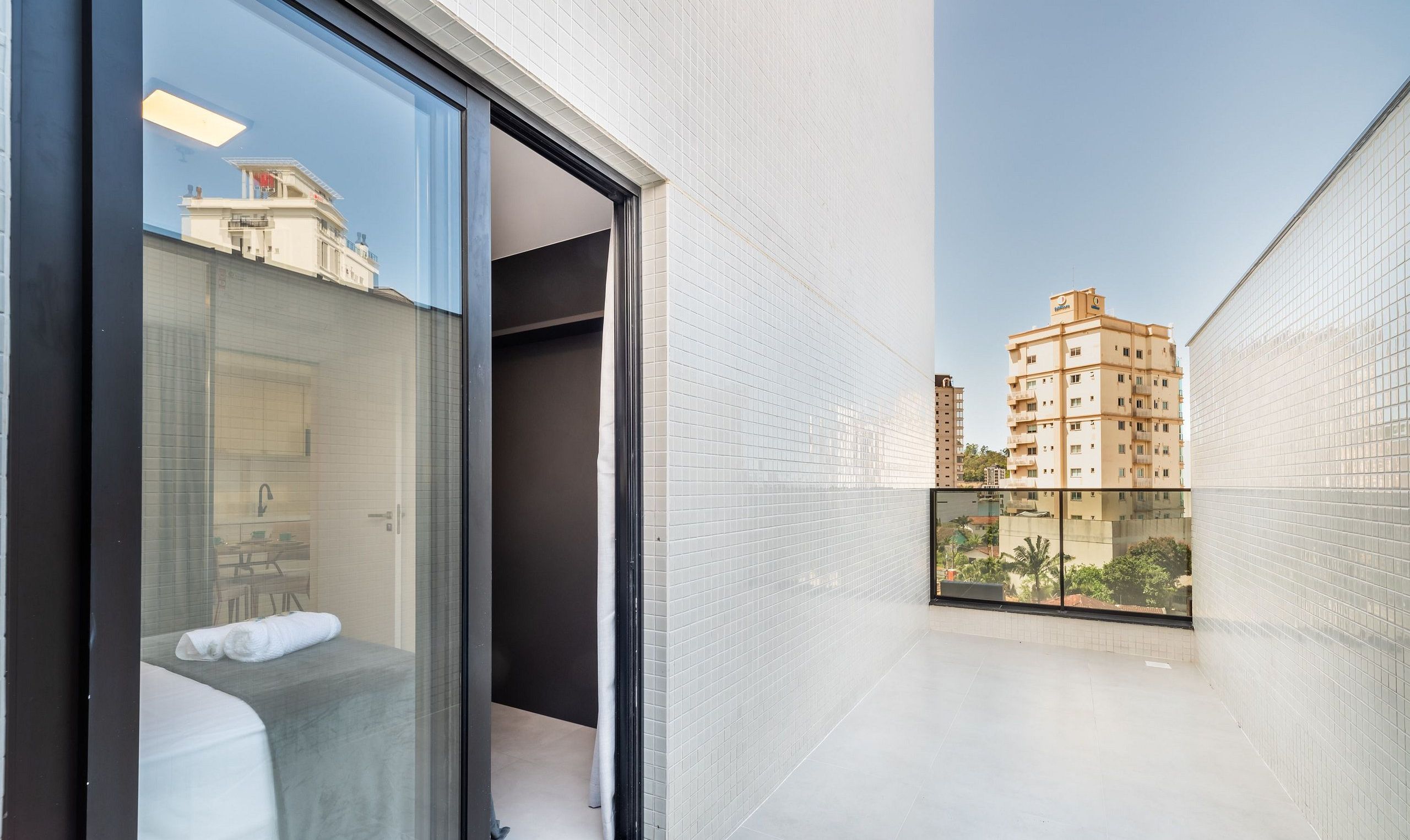 Une chambre d’hôtel avec une porte vitrée donnant sur un balcon, un lit et une salle de bain.