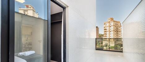 Une chambre d’hôtel avec une porte vitrée donnant sur un balcon, un lit et une salle de bain.