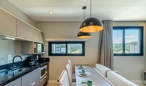 A modern kitchen with a dining area, a view of the city, and a large window. - MHF III Apts Variados a 280m da Praia em Itapema (Itapema)