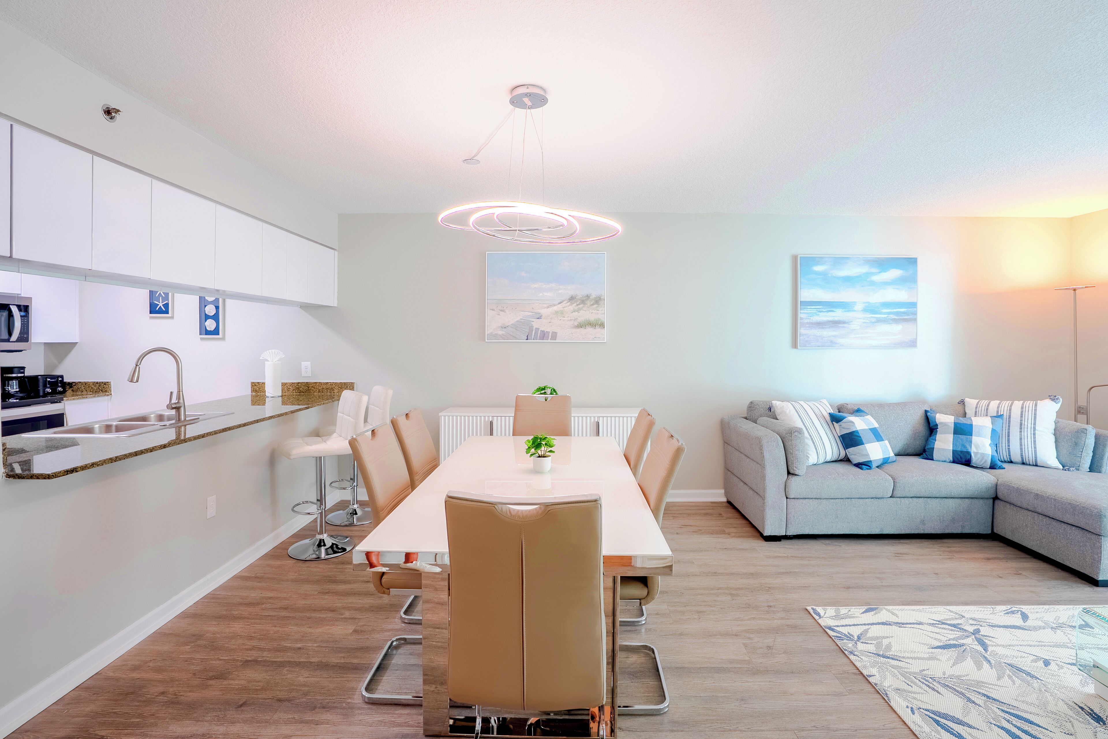 A modern living room with a dining table, sofa, and kitchen area.