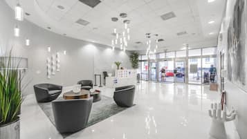 A modern lobby with a reception desk, seating area, and a glass entrance.