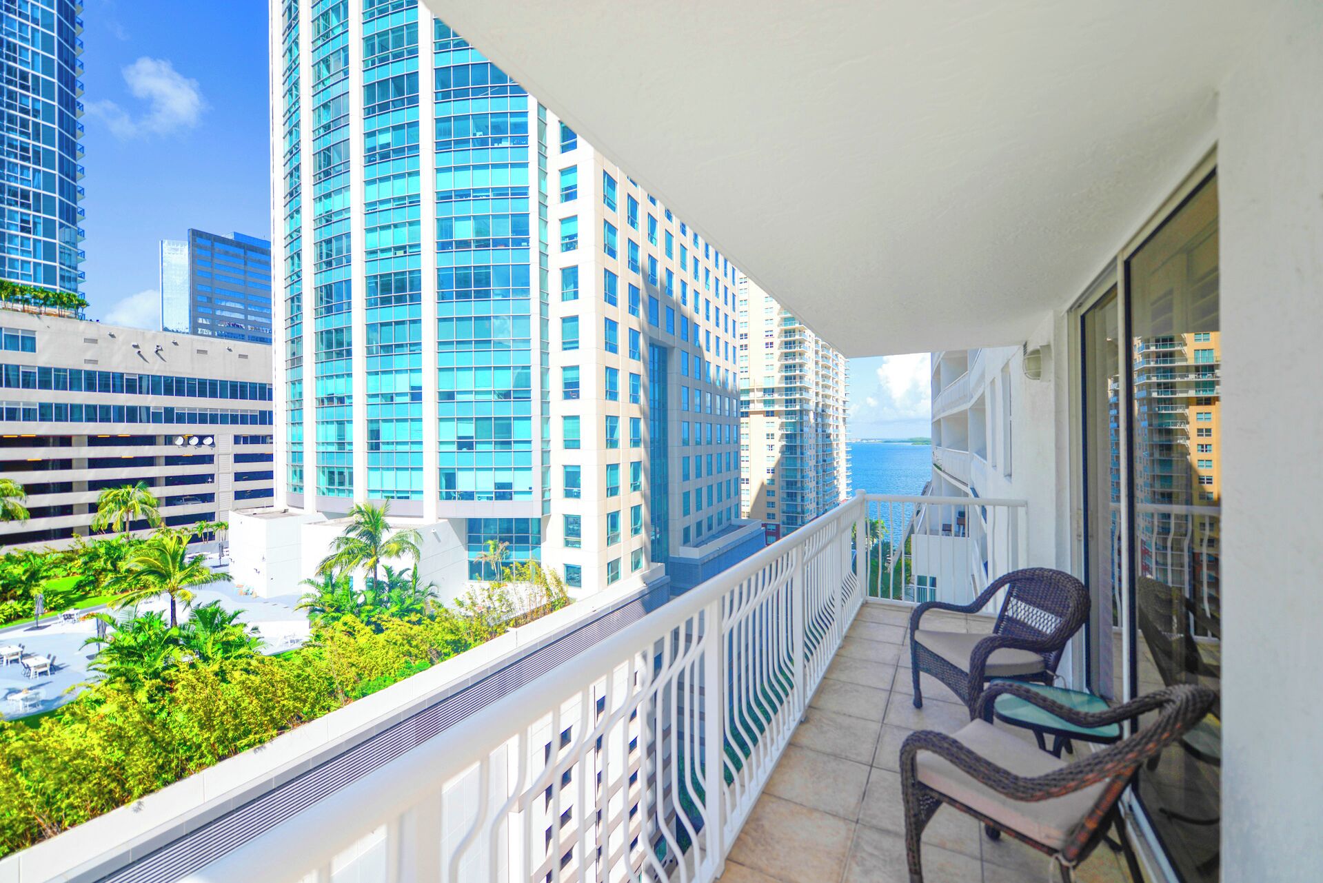 A balcony with a view of high-rise buildings and the ocean.
