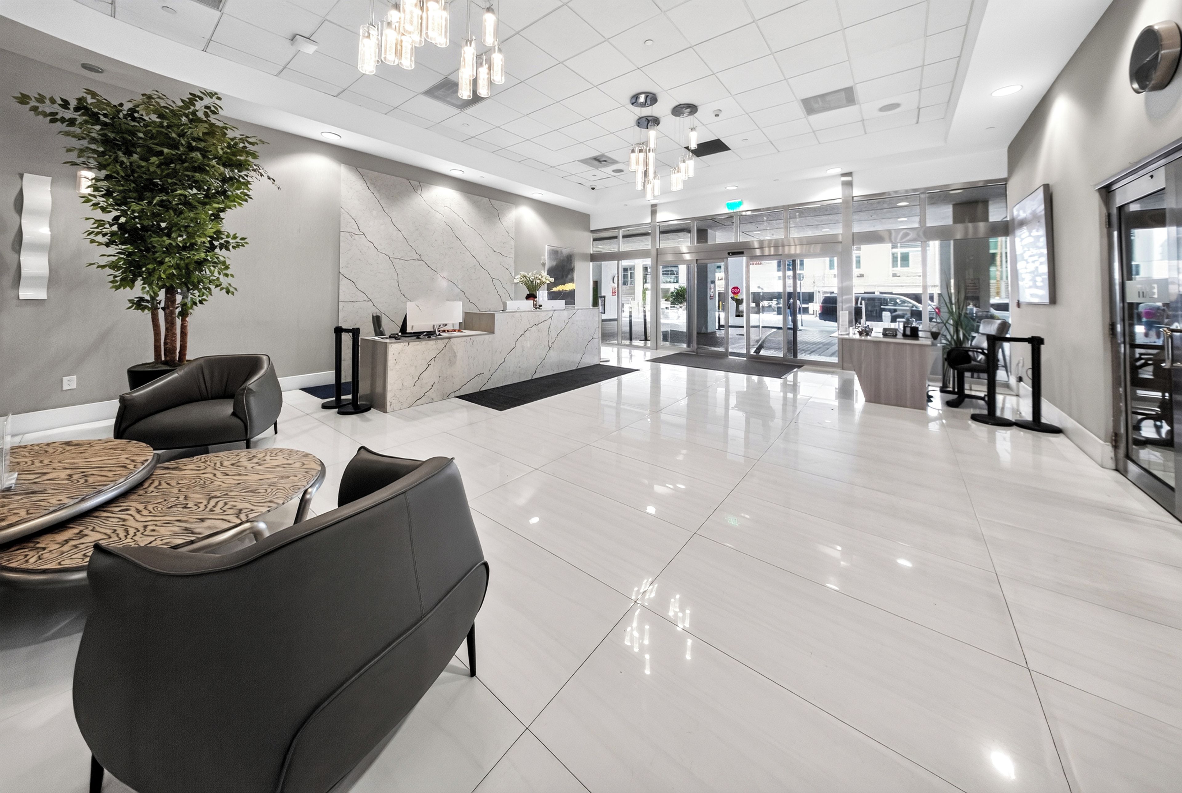 Eine moderne Lobby mit Empfangstresen, Sitzgelegenheiten und einer großen Pflanze.
