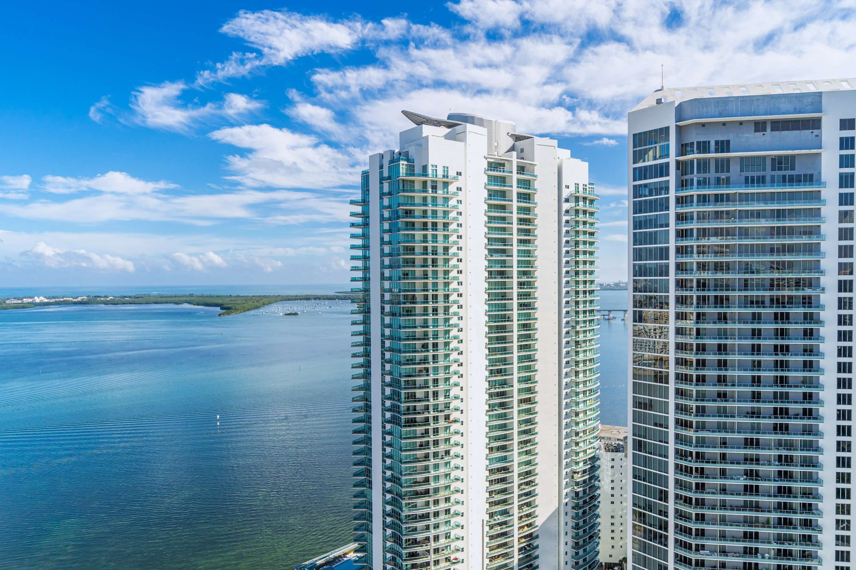 Two high-rise buildings with a view of the water and a clear sky.