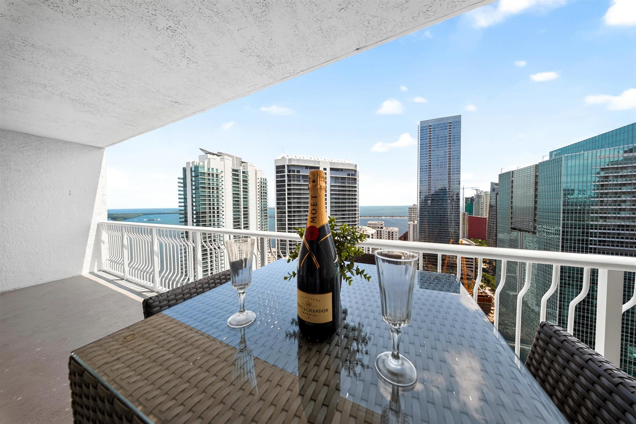 Un balcon avec une table, une bouteille de champagne et deux verres.