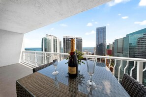 Un balcon avec une table, une bouteille de champagne et deux verres.