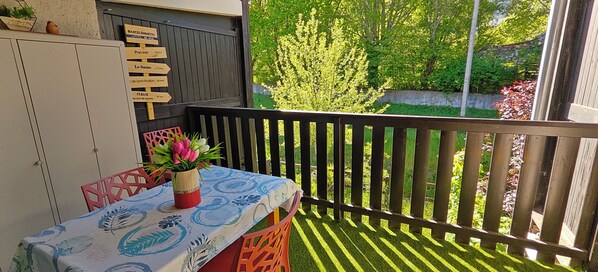 A balcony with a table, chairs, and a potted plant.