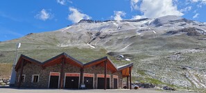 A mountain lodge with a stone facade, multiple entry/exit doors, and a sign indicating services like 'Uscita' and 'Sortie.' - Cozy studio in Barcelonnette (Barcelonnette)