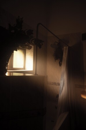 A dimly lit room with a window, a shower area, and a potted plant. - QASA Valle Sagrado by Nomad (Calca)