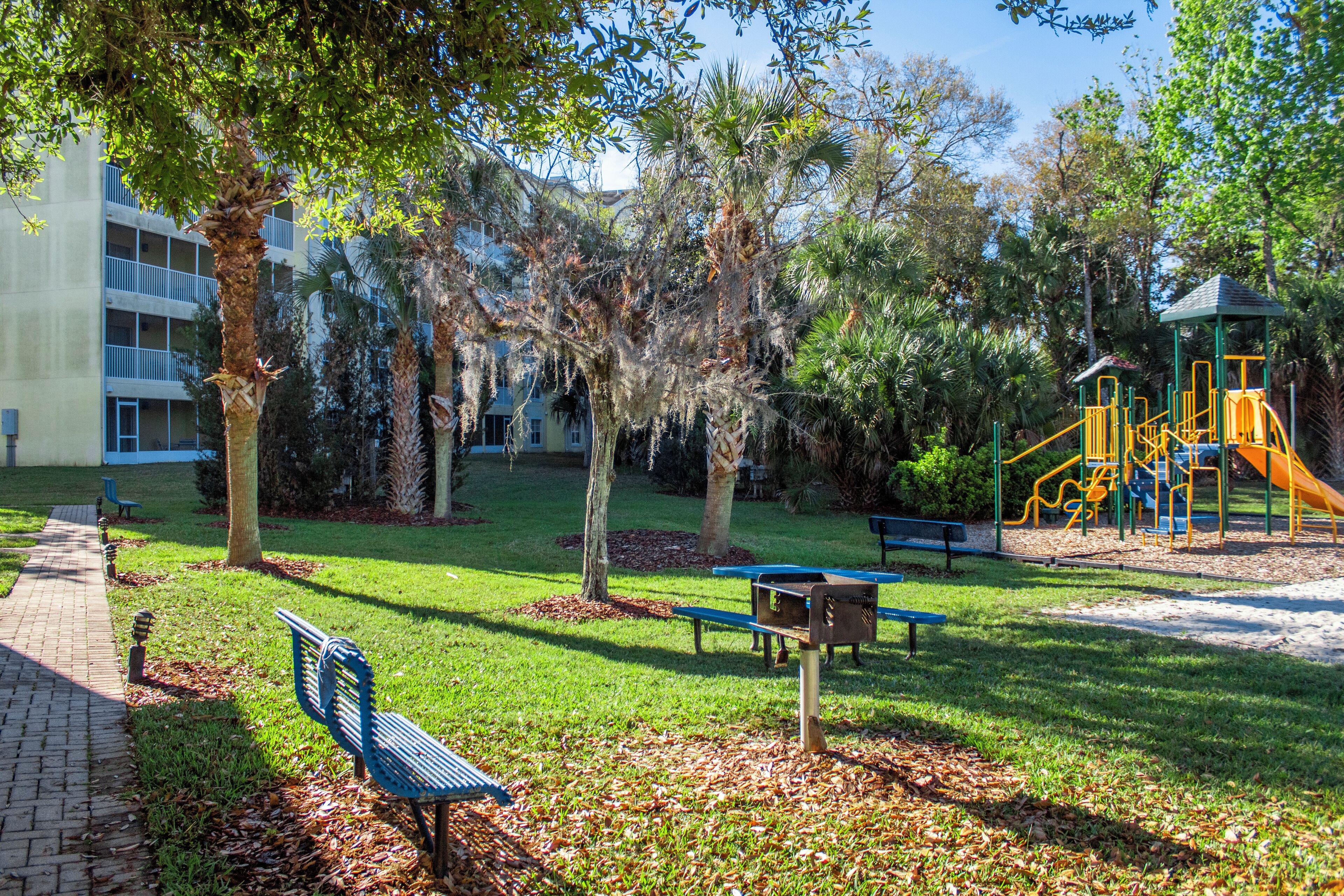 A park with a playground, benches, and trees.