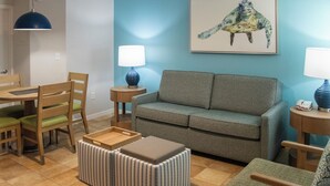 A living room with a grey sofa, a wooden dining table with chairs, a blue lamp, and a framed artwork of a sea turtle on the wall. - Barefoot'n Resort Kissimmee Orlando (Kissimmee)